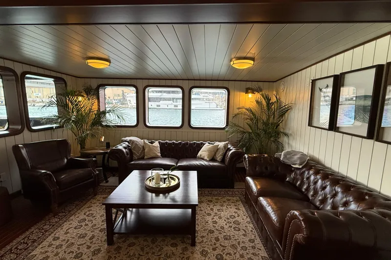 Anne S Pierce Yacht Photos Pics Luxurious ship interior with leather sofas, wooden table, and large windows, Glovertown Shipyard 2021.