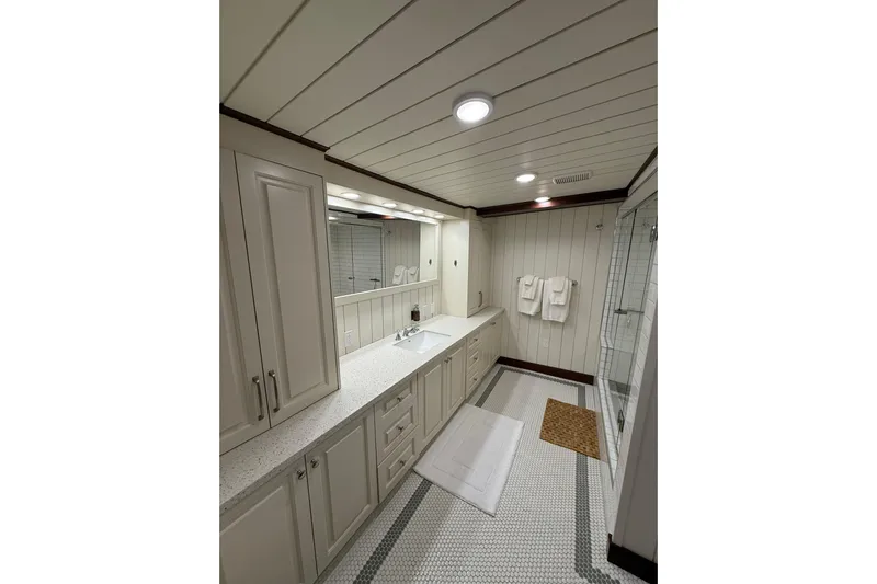 Anne S Pierce Yacht Photos Pics Luxurious ship bathroom with modern fixtures, white cabinetry, and glass shower, Glovertown Shipyard 2021.