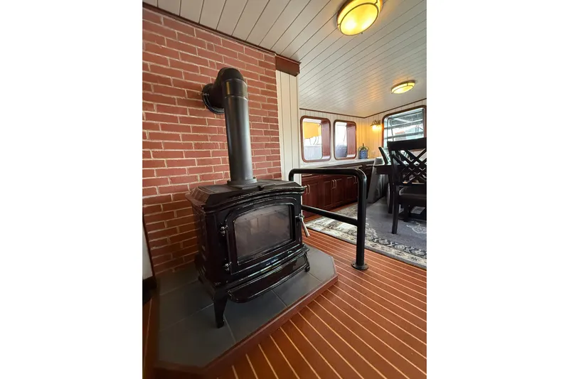 Anne S Pierce Yacht Photos Pics Cozy ship interior with wood stove, brick wall, and dining area, Custom Glovertown Shipyard 2021.