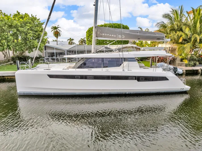 Yacht Photos Pics 2021 Leopard 50 catamaran docked on a calm waterway, surrounded by lush greenery.