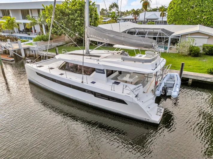 Yacht Photos Pics 2021 Leopard 50 catamaran docked by waterfront homes, featuring sleek design and spacious deck.