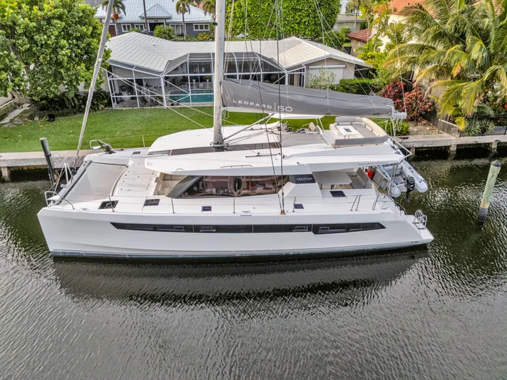  Yacht Photos Pics Modern 2021 Leopard 50 catamaran docked by lush waterfront property.