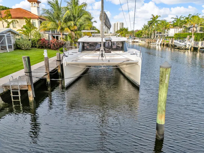  Yacht Photos Pics 2021 Leopard 50 catamaran docked in a scenic canal with palm trees.