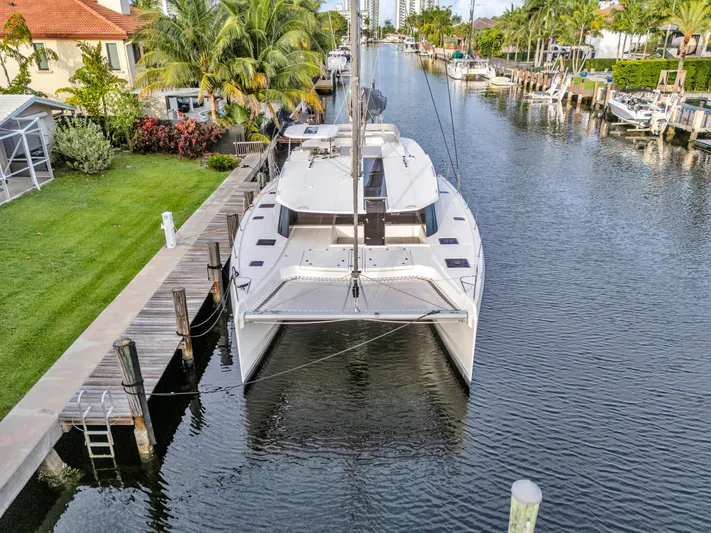  Yacht Photos Pics Leopard 50 catamaran docked in a scenic canal, surrounded by lush greenery.