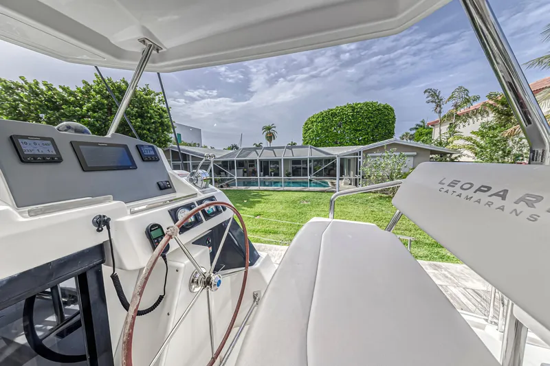  Yacht Photos Pics Helm of 2021 Leopard 50 catamaran with view of modern house and lush garden.