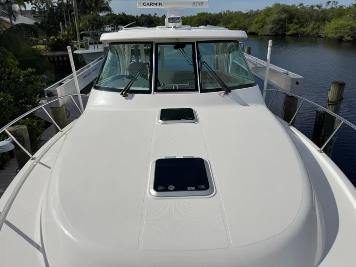 Yacht Photos Pics 2015 Pursuit OS 385 Offshore boat docked by a serene waterway.