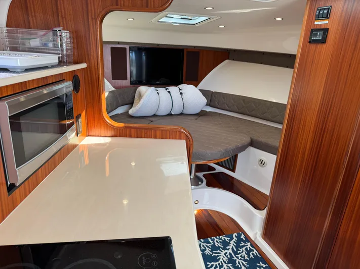  Yacht Photos Pics 2015 Pursuit OS 385 Offshore interior with cozy seating, microwave, and elegant wood finish.