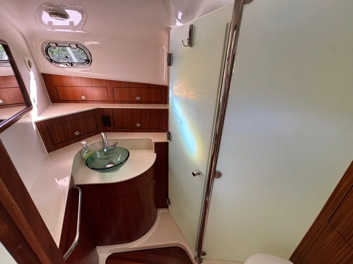  Yacht Photos Pics Luxurious bathroom interior of 2015 Pursuit OS 385 Offshore boat with glass sink and wooden cabinets.