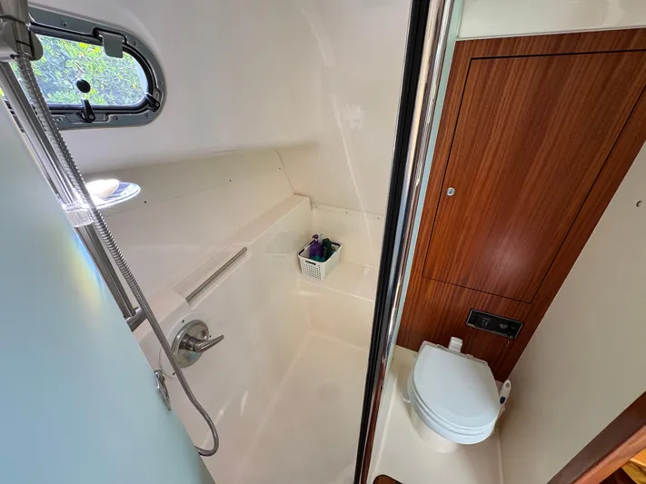  Yacht Photos Pics 2015 Pursuit OS 385 Offshore bathroom with shower, toilet, and wooden cabinet.