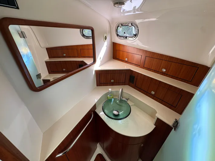  Yacht Photos Pics Luxurious bathroom in 2015 Pursuit OS 385 Offshore boat with wood cabinets and glass sink.