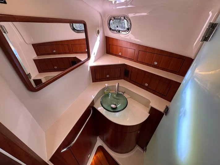 Yacht Photos Pics Luxurious bathroom in 2015 Pursuit OS 385 Offshore boat with wood cabinetry and glass sink.
