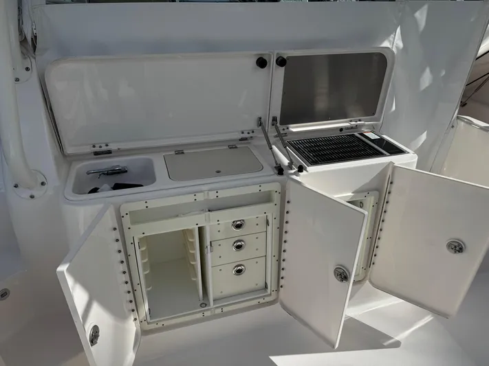  Yacht Photos Pics 2015 Pursuit OS 385 Offshore boat kitchen with sink, grill, and storage cabinets.