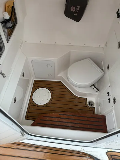  Yacht Photos Pics 2023 Everglades 285 Center Console boat interior with toilet and wooden flooring.