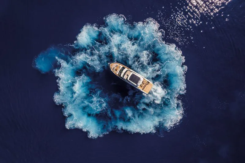 Absolute 60 Fly Yacht Photos Pics Aerial view of 2025 Absolute 60 Fly yacht creating circular wake in deep blue ocean.