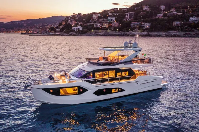 Absolute 60 Fly Yacht Photos Pics Luxurious 2025 Absolute 60 Fly yacht cruising at sunset near coastal town.