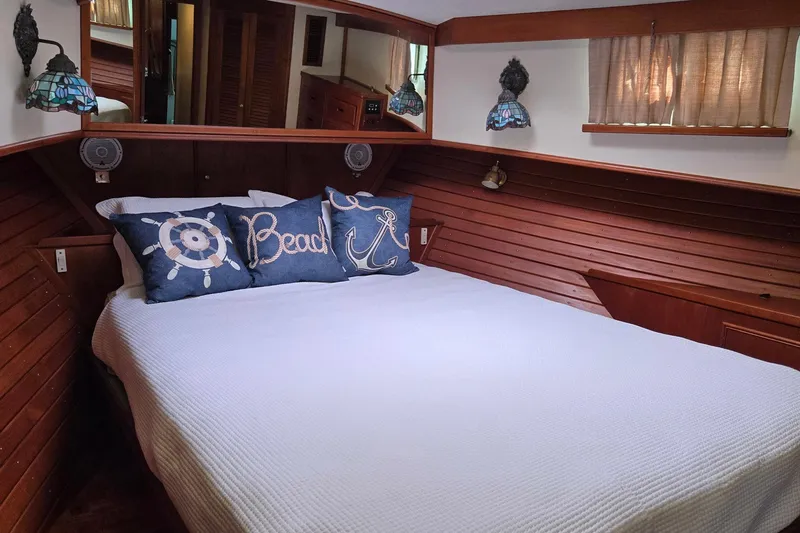 Safari Yacht Photos Pics Cozy bedroom in 1997 Grand Banks 46 Europa yacht with nautical-themed pillows and wooden paneling.