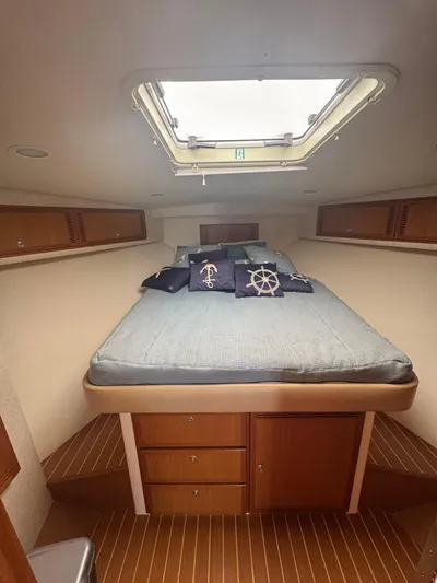 Cayuco Yacht Photos Pics 2010 Cabo 40 Express cabin interior with bed, nautical-themed pillows, and overhead hatch.