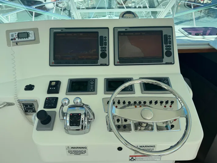 Cayuco Yacht Photos Pics Control panel of a 2010 Cabo 40 Express boat with dual screens and steering wheel.