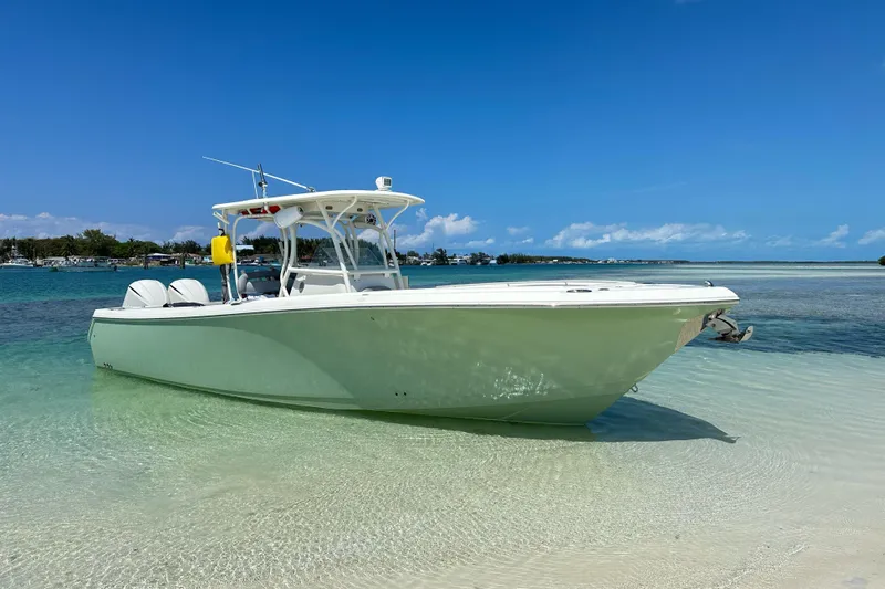 Why Knot Yacht Photos Pics 2014 Sailfish 320 CC boat anchored on clear, shallow water with a sunny sky backdrop.