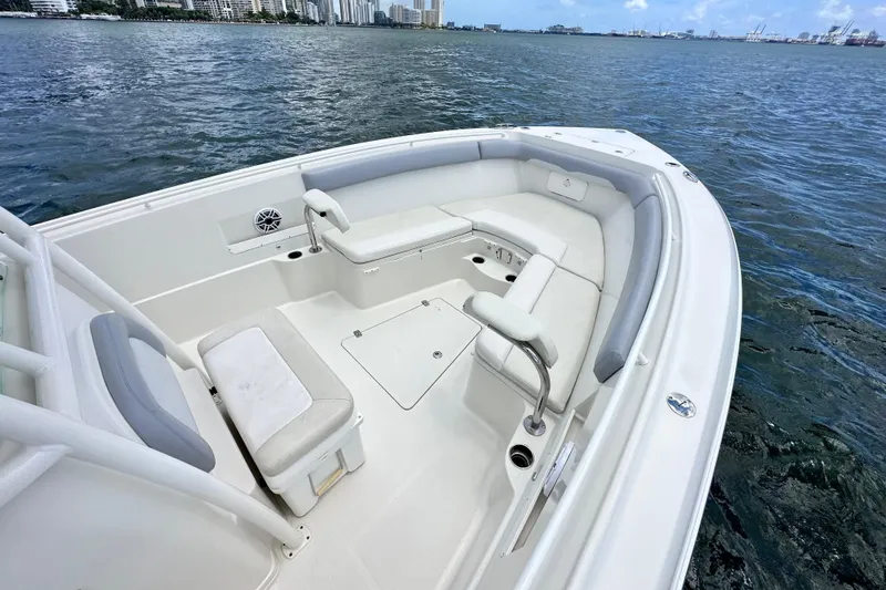 Why Knot Yacht Photos Pics 2014 Sailfish 320 CC boat with spacious seating, on calm waters, city skyline in background.