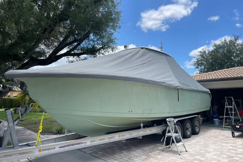Why Knot Yacht Photos Pics 2014 Sailfish 320 CC boat on trailer, covered, parked in driveway under blue sky.