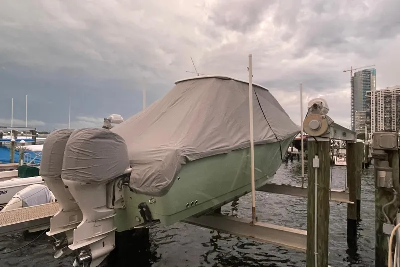Why Knot Yacht Photos Pics Covered 2014 Sailfish 320 CC boat on lift at marina, cloudy sky background.