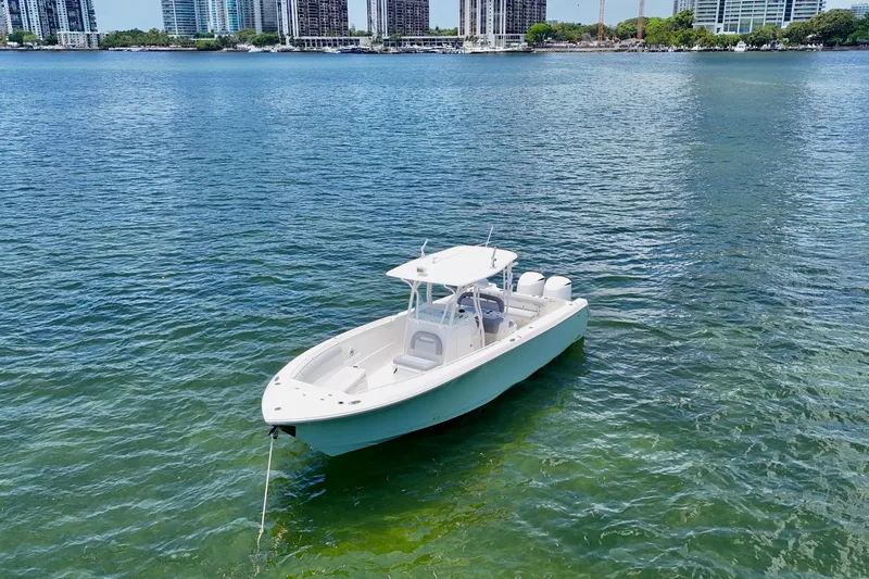 Why Knot Yacht Photos Pics 2014 Sailfish 320 CC boat on calm water with city skyline background.