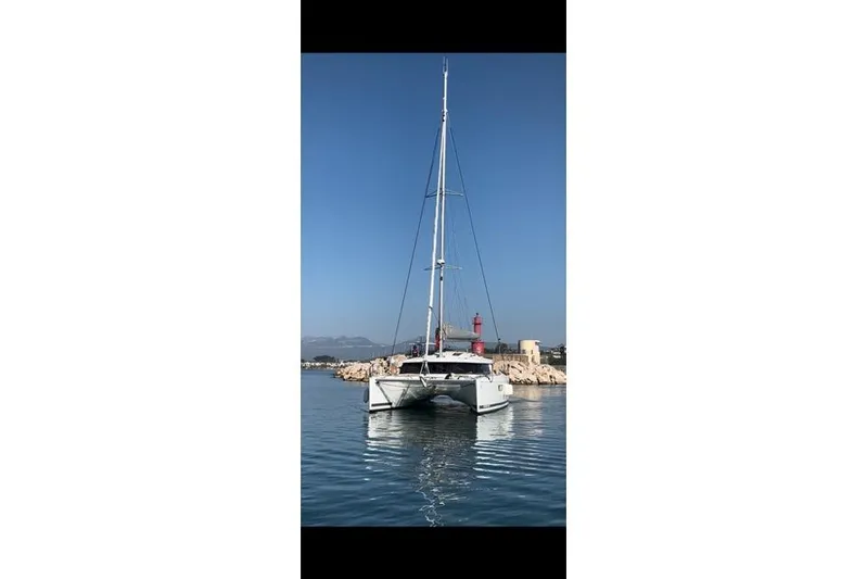 Sanouva Yacht Photos Pics 2019 Fountaine Pajot SABA 50 catamaran sailing near a rocky coastline.
