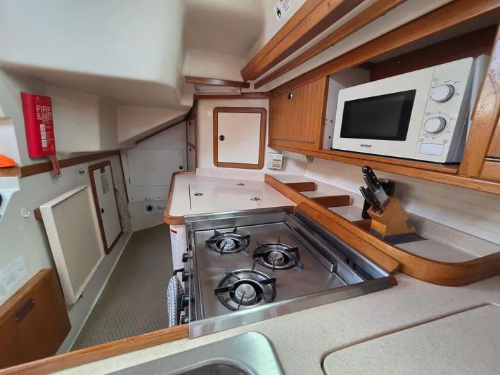  Yacht Photos Pics Galley kitchen in 2000 Catalina 42 MkII yacht with stove, microwave, and wooden cabinetry.