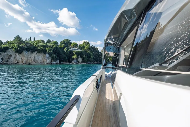 M8-15 Yacht Photos Pics 2023 Bluegame BGX 63 yacht cruising near scenic coastline under blue sky.