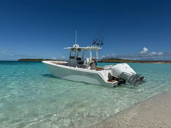  Yacht Photos Pics 2025 Pair Customs 28 Center Console boat in clear turquoise water near a sandy beach.