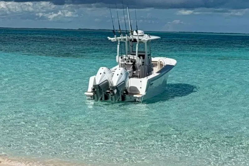  Yacht Photos Pics 2025 Pair Customs 28 Center Console boat in clear turquoise water near a sandy beach.