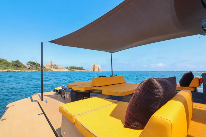 Gustavia I Yacht Photos Pics Luxurious 2021 OKEAN 55 yacht with yellow seating, cruising near a scenic coastal view.