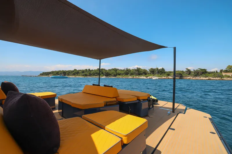 Gustavia I Yacht Photos Pics Luxurious 2021 OKEAN 55 yacht with sunshade and seating, cruising near a scenic coastline.