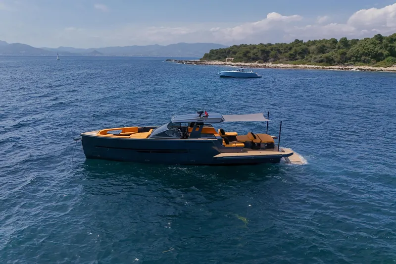 Gustavia I Yacht Photos Pics Luxury 2021 OKEAN 55 yacht anchored in serene blue waters near a lush coastline.