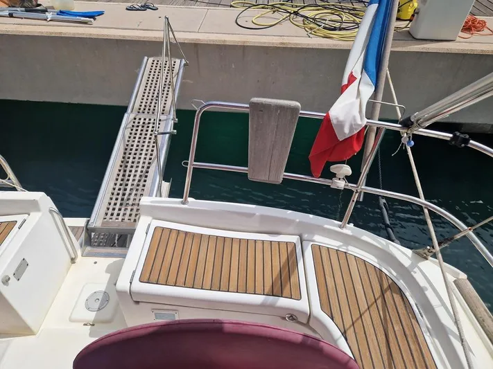  Yacht Photos Pics Beneteau Oceanis 473 Clipper yacht stern with wooden deck and flag, docked at marina.