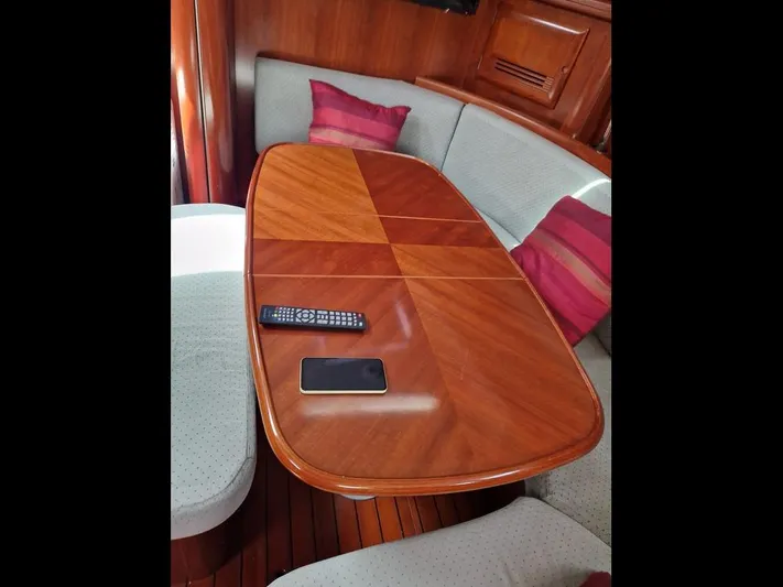  Yacht Photos Pics Interior of 2001 Beneteau Oceanis 473 Clipper with wooden table and cushioned seating.