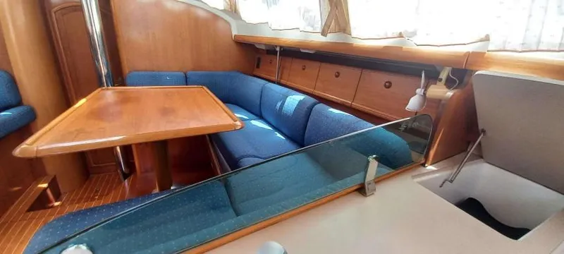Happy Destiny Yacht Photos Pics 2004 Jeanneau Sun Odyssey 43 DS interior with blue seating and wooden table.