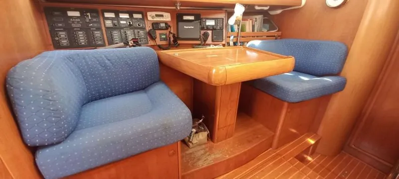Happy Destiny Yacht Photos Pics Interior of 2004 Jeanneau Sun Odyssey 43 DS with blue cushioned seating and navigation equipment.