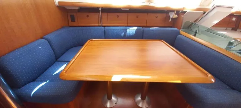 Happy Destiny Yacht Photos Pics Interior of 2004 Jeanneau Sun Odyssey 43 DS with wooden table and blue seating.