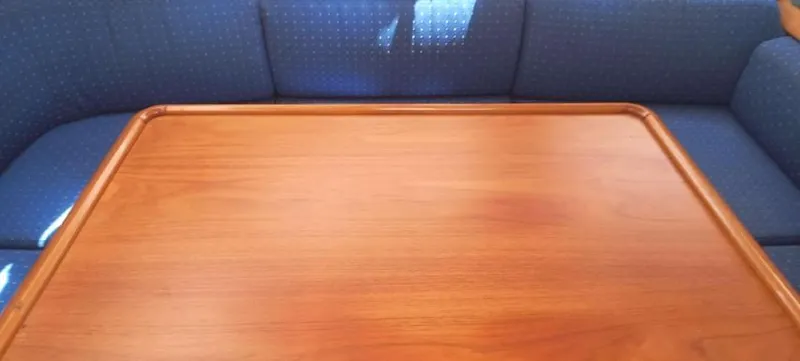 Happy Destiny Yacht Photos Pics Interior of 2004 Jeanneau Sun Odyssey 43 DS with wooden table and blue seating.