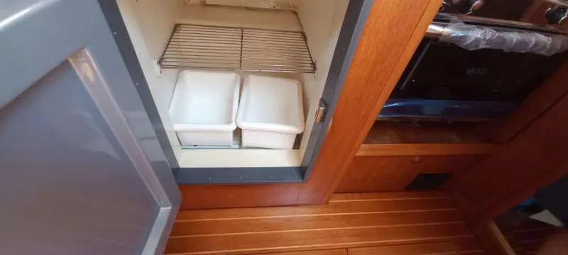 Happy Destiny Yacht Photos Pics Interior of 2004 Jeanneau Sun Odyssey 43 DS showing storage compartment with containers.