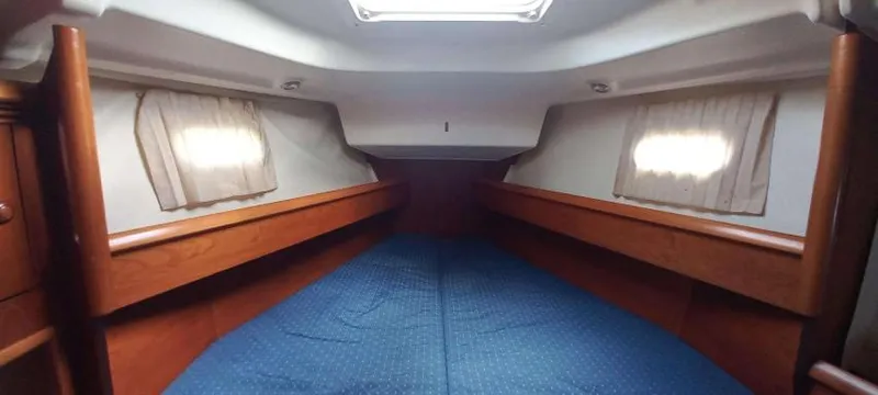 Happy Destiny Yacht Photos Pics Interior cabin of 2004 Jeanneau Sun Odyssey 43 DS with blue bedding and wooden accents.