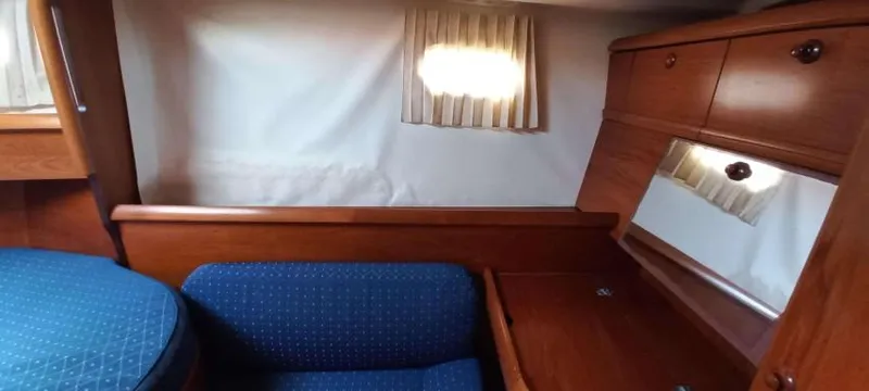 Happy Destiny Yacht Photos Pics Interior of 2004 Jeanneau Sun Odyssey 43 DS with wooden cabinetry and blue upholstery.