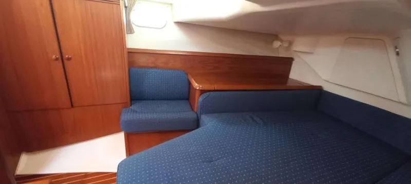Happy Destiny Yacht Photos Pics Interior cabin of 2004 Jeanneau Sun Odyssey 43 DS with blue upholstery and wooden cabinetry.