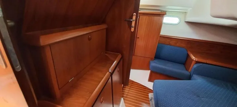 Happy Destiny Yacht Photos Pics Interior of 2004 Jeanneau Sun Odyssey 43 DS, featuring wood cabinetry and blue seating.