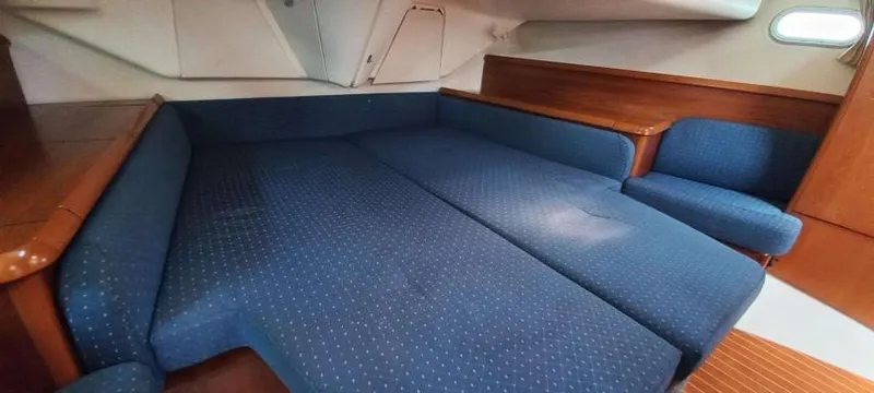 Happy Destiny Yacht Photos Pics Interior cabin of 2004 Jeanneau Sun Odyssey 43 DS with blue upholstery and wooden accents.