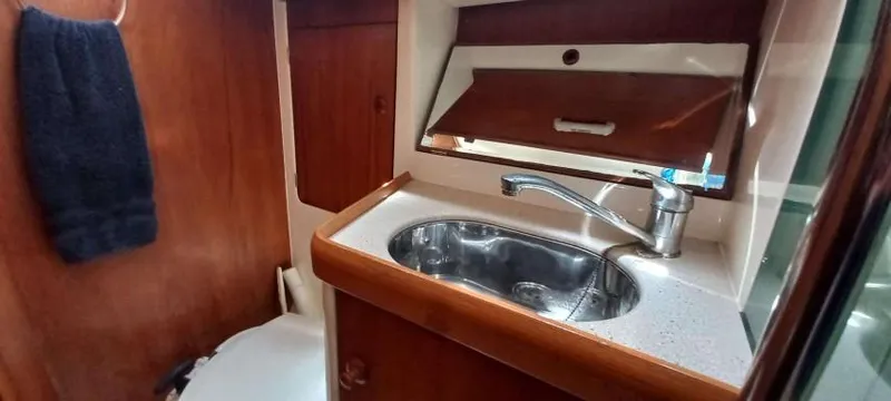 Happy Destiny Yacht Photos Pics 2004 Jeanneau Sun Odyssey 43 DS bathroom with sink, wooden cabinetry, and towel.