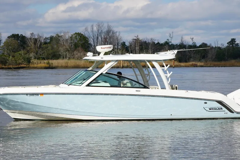  Yacht Photos Pics 2021 Boston Whaler 320 Vantage boat on calm water, with trees in the background.