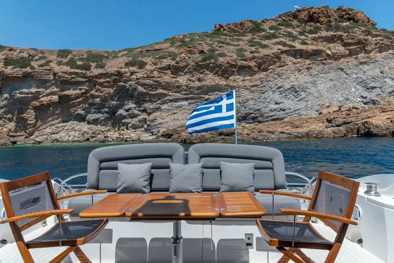 M/y Seaduced Yacht Photos Pics Sunseeker Predator 52 yacht with Greek flag, rocky coastline backdrop, 2009 model.